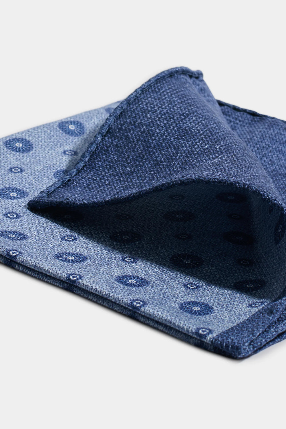 Blue patterned fabric with a folded section on a white background