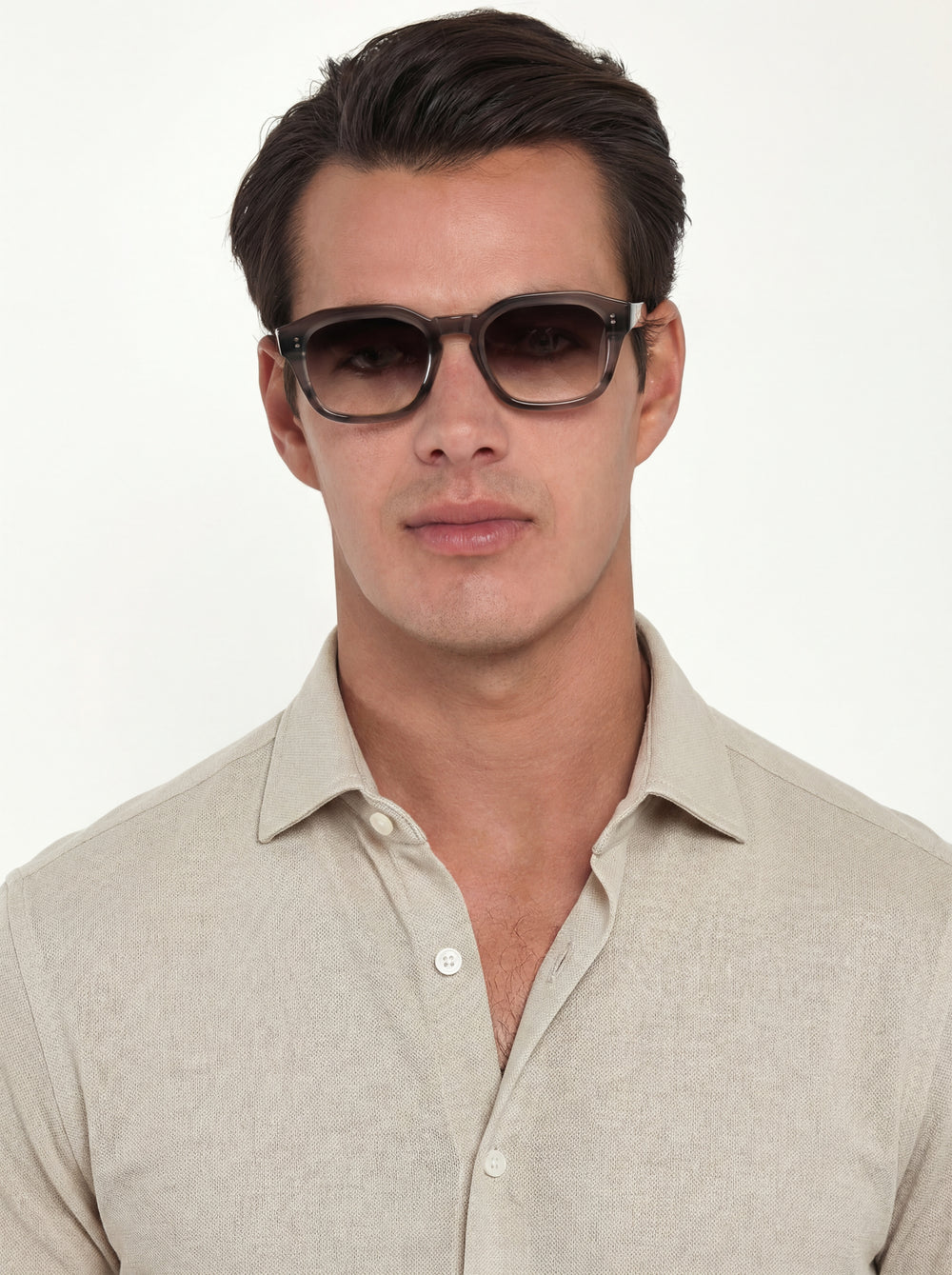 Man wearing sunglasses and a light-colored shirt on a white background