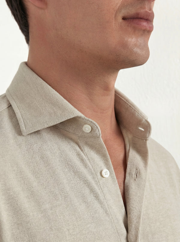 Close-up of a man wearing a beige shirt with a white background