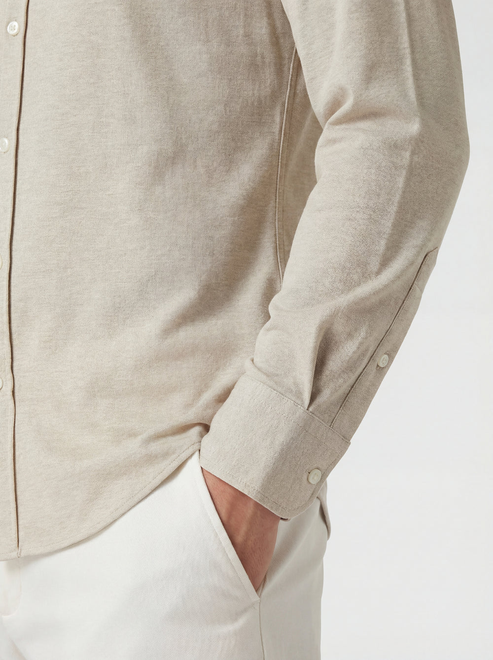 Close-up of a beige button-up shirt with rolled-up sleeves on a white background