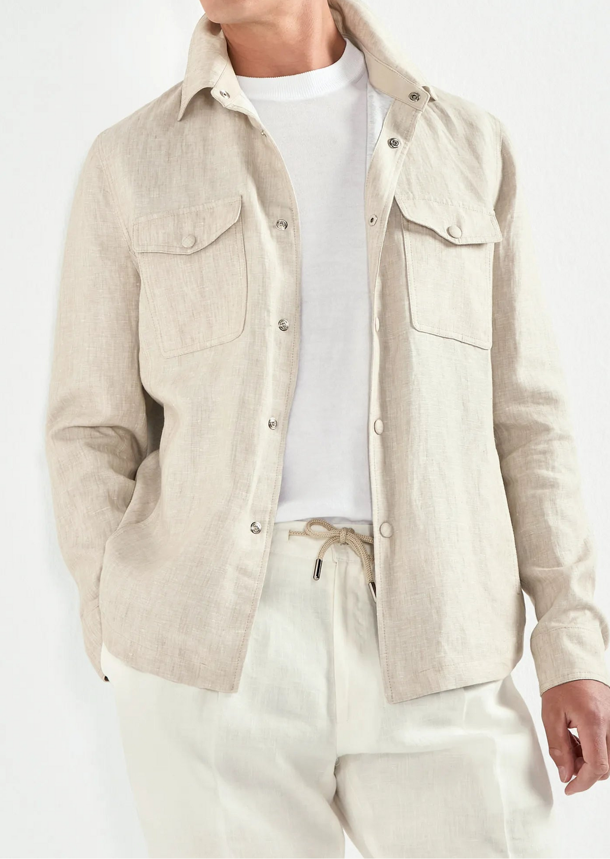 Man wearing a beige jacket, white shirt, and pants against a white background