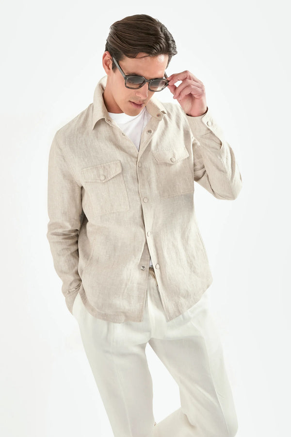 Man wearing a beige linen shirt and white pants on a white background
