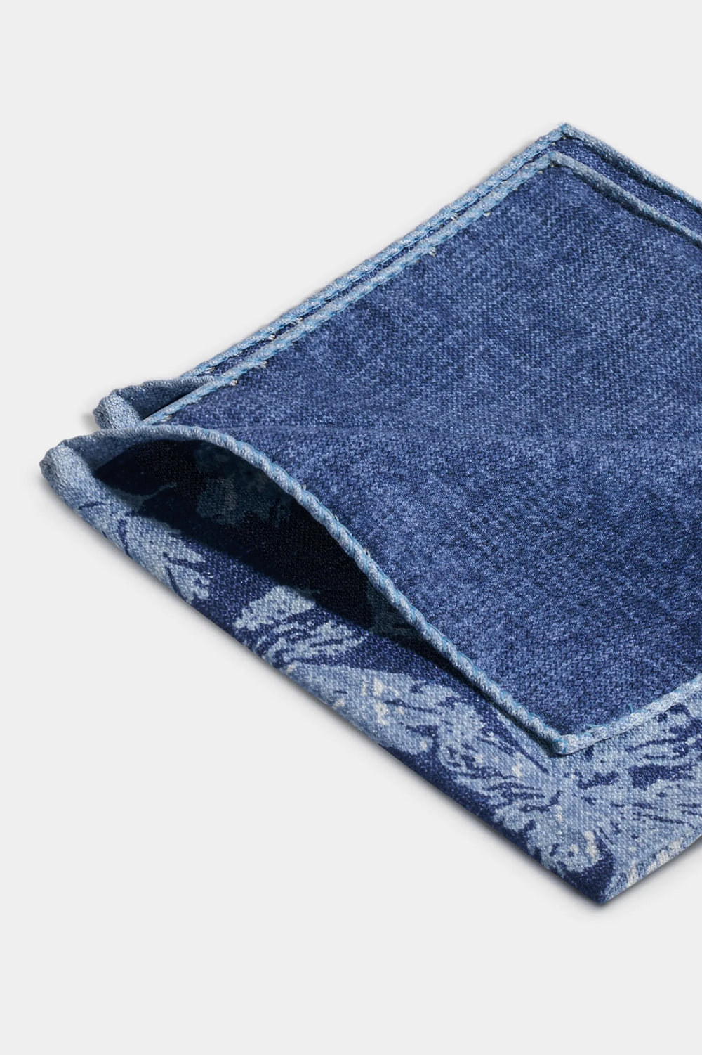 Folded blue fabric with lace trim on a white background