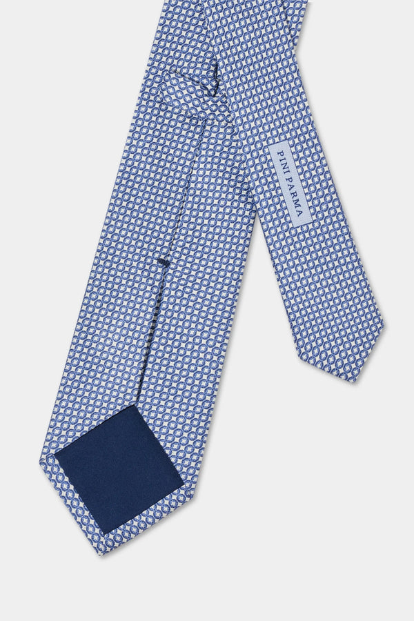 Blue patterned tie with a pocket square on a light gray background
