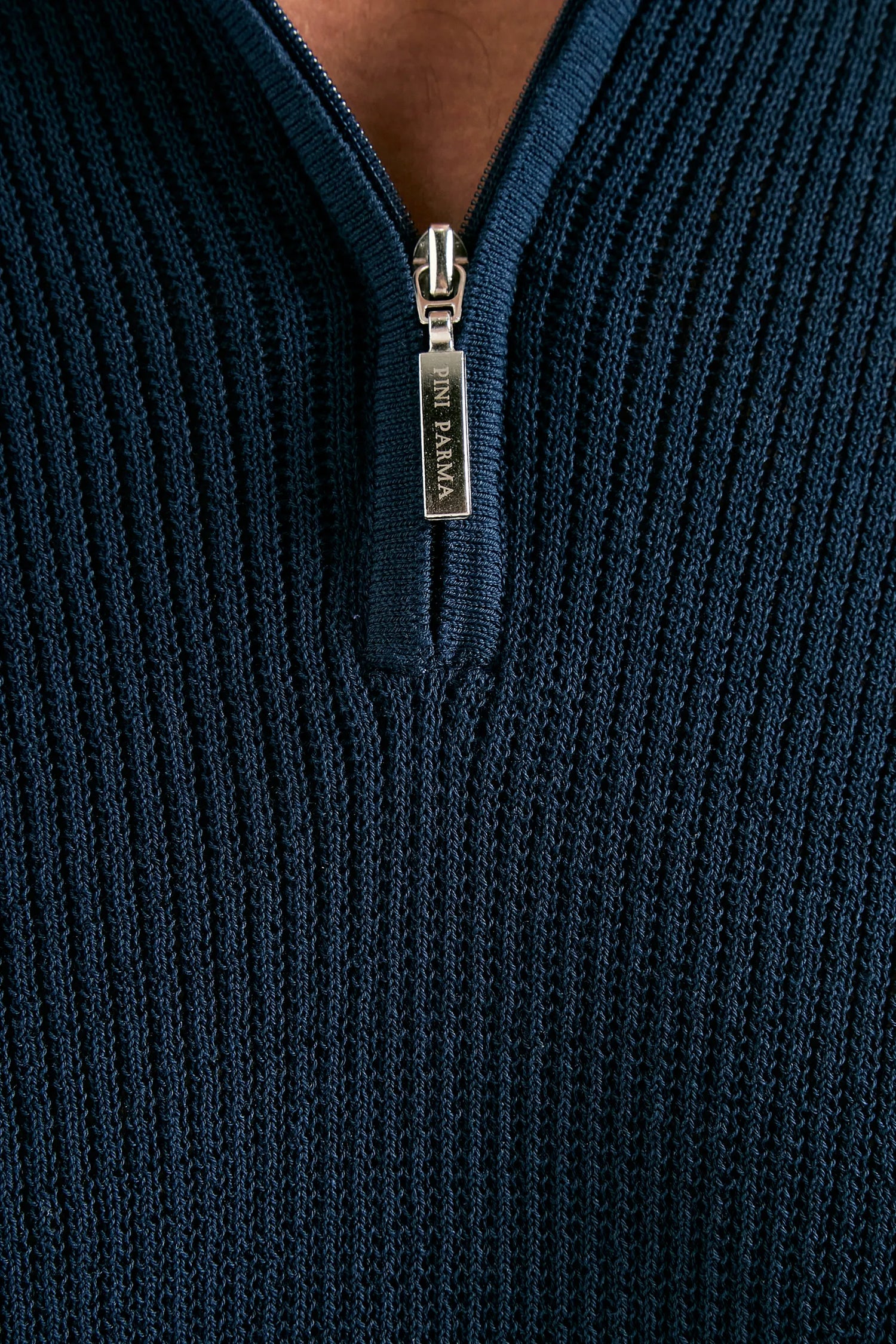 Close-up of a navy blue ribbed sweater with a zipper