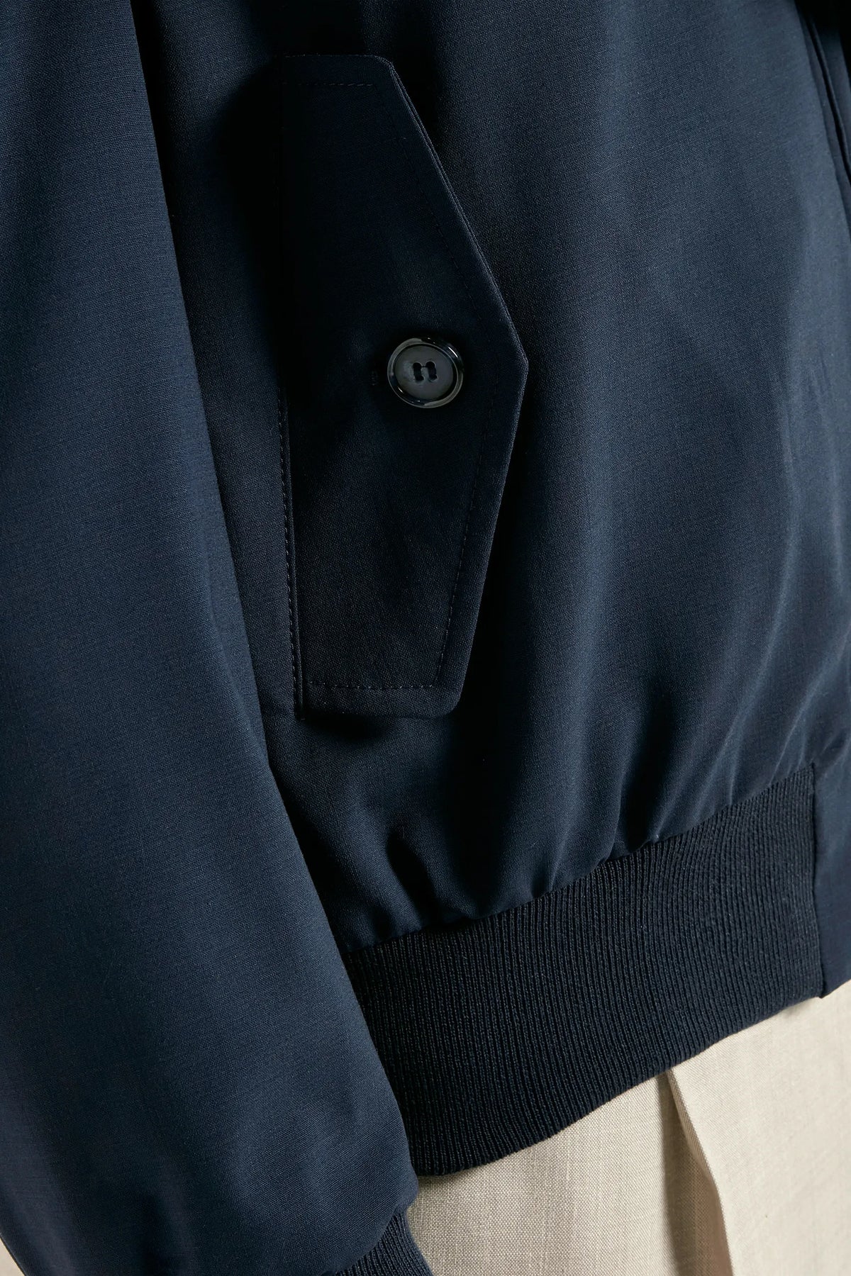 Close-up of a navy blue jacket with a button on a neutral background