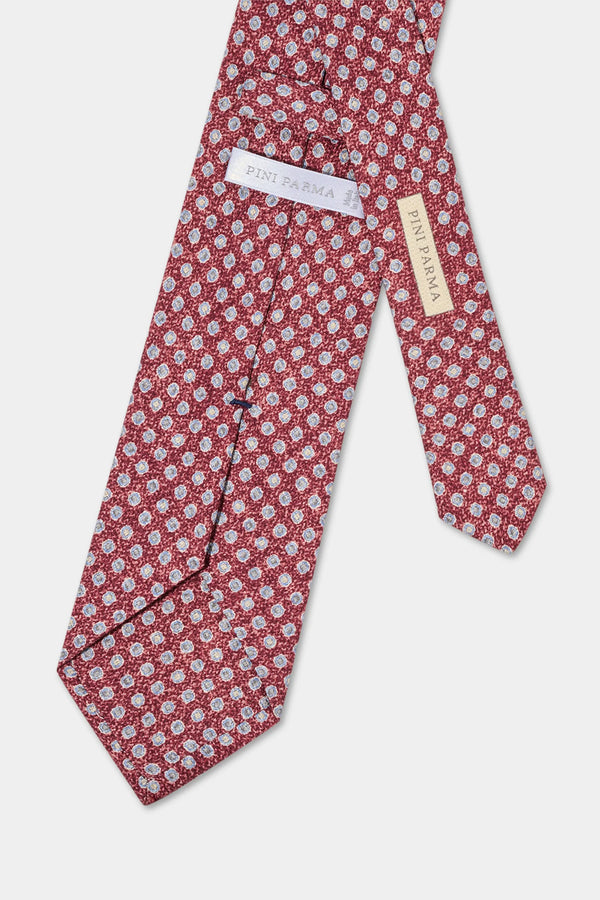 Red floral patterned tie with brand label on a light gray background