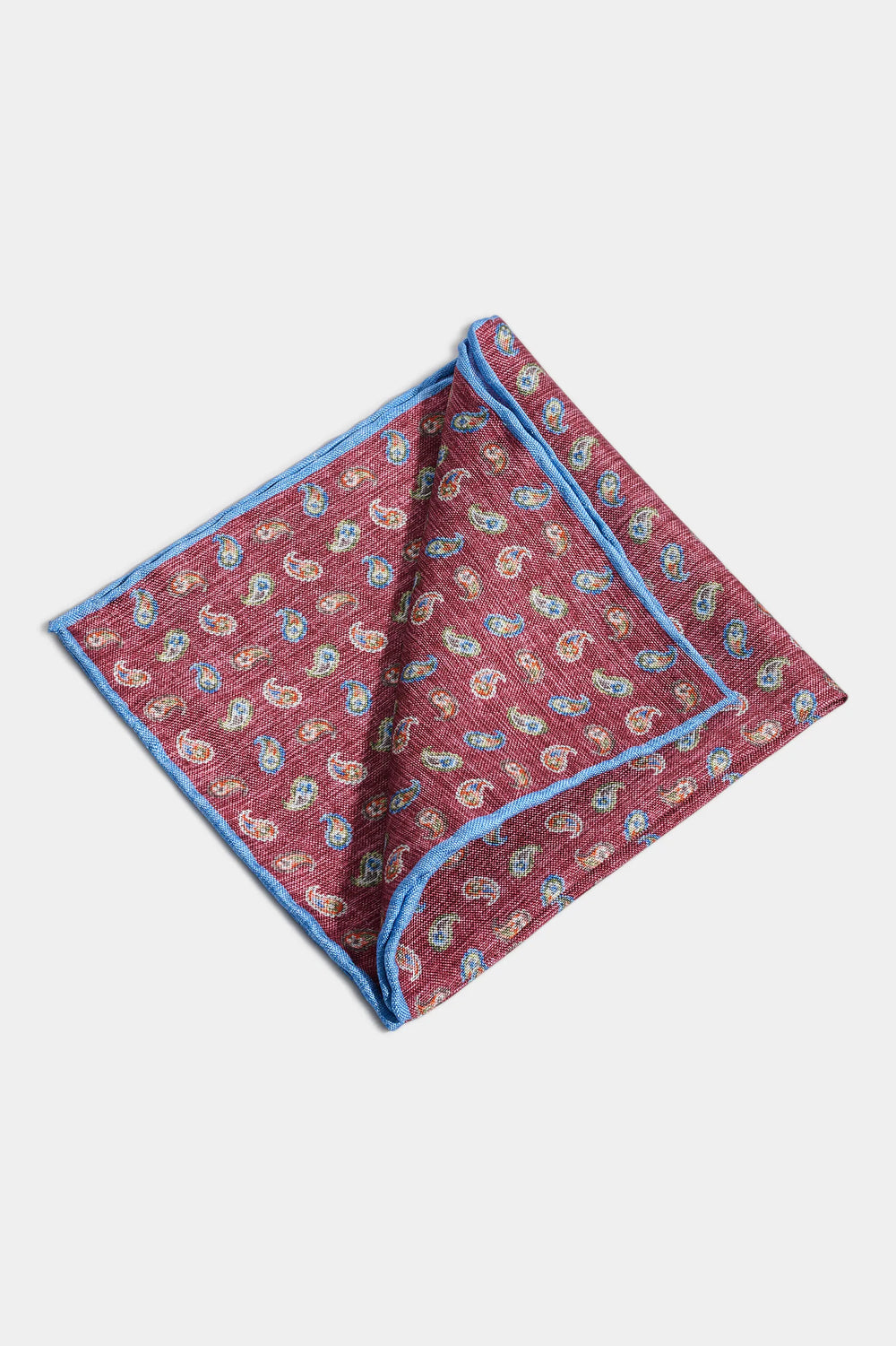Folded red paisley pocket square with blue border on a white background