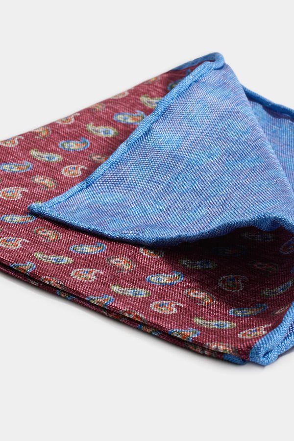 Folded fabric with paisley pattern on one side and blue textured fabric on the other, on a white background.