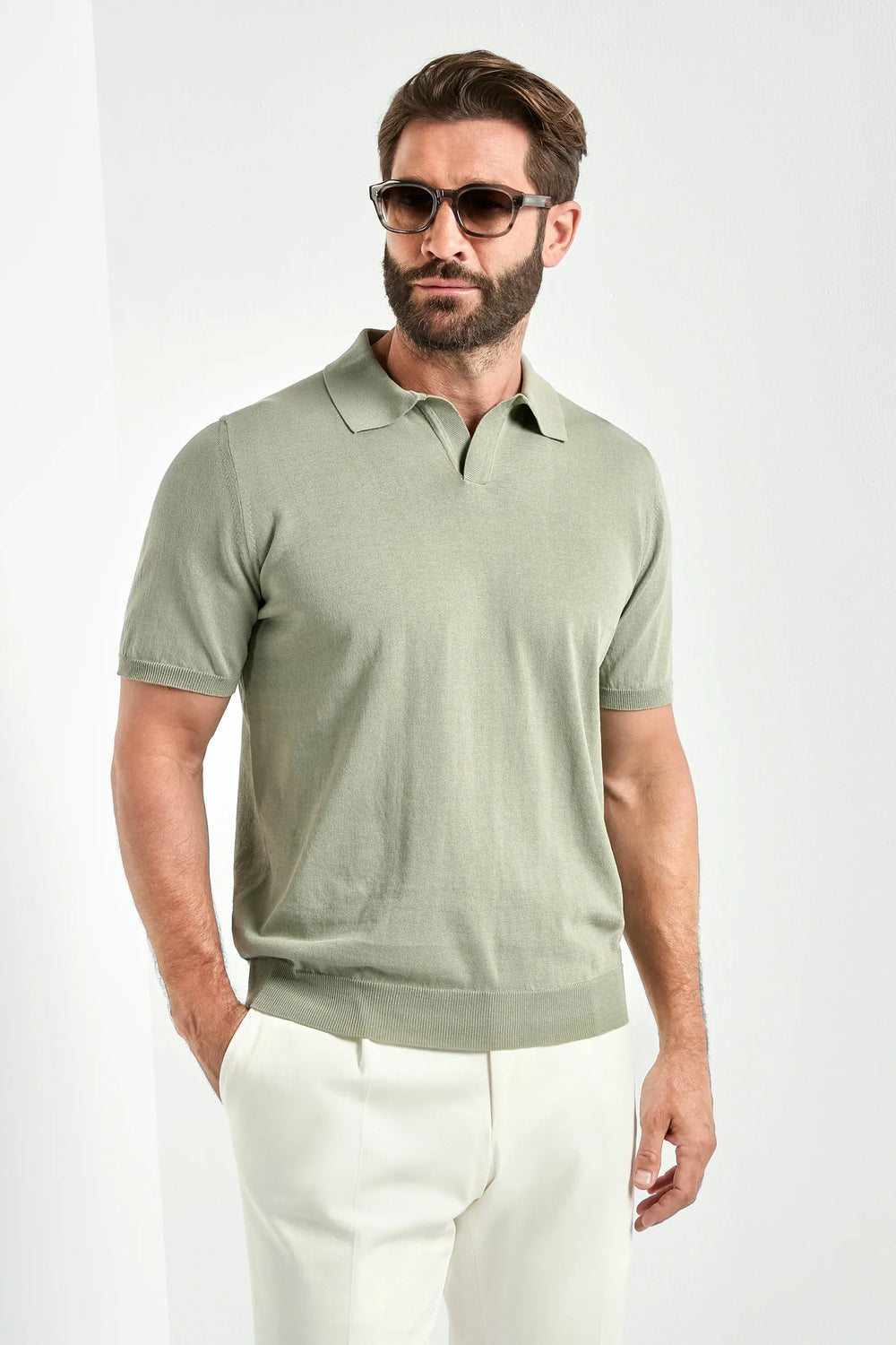 Man wearing a green polo shirt and white pants on a white background