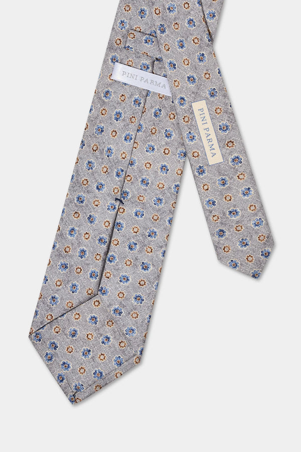 Floral patterned tie with a brand label on a light gray background