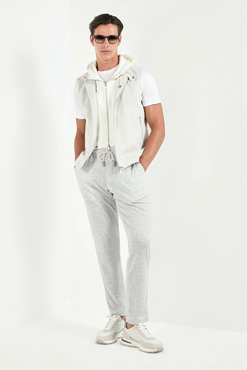 Man wearing a white outfit with gray pants on a white background