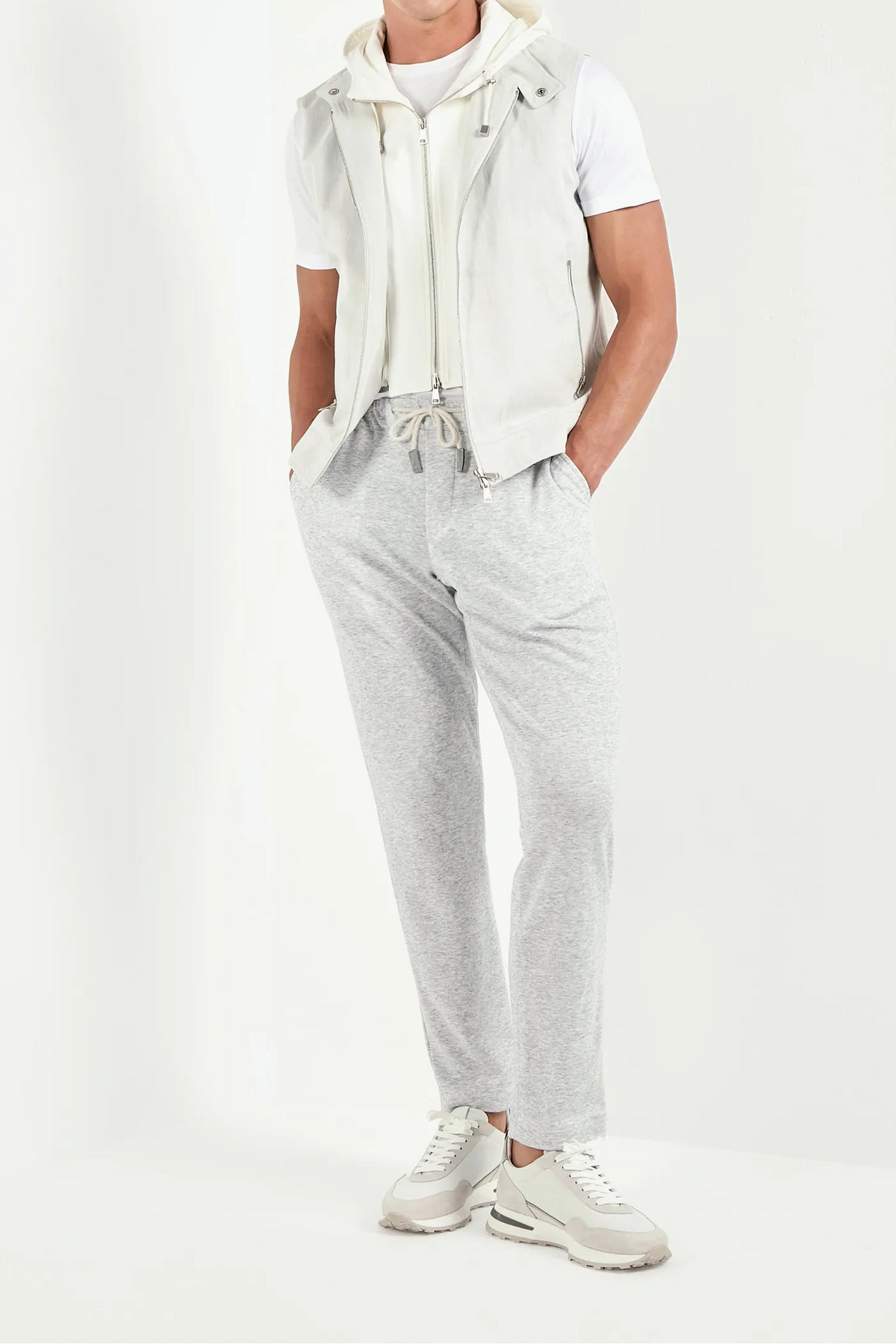 Man wearing a white outfit with gray pants on a white background