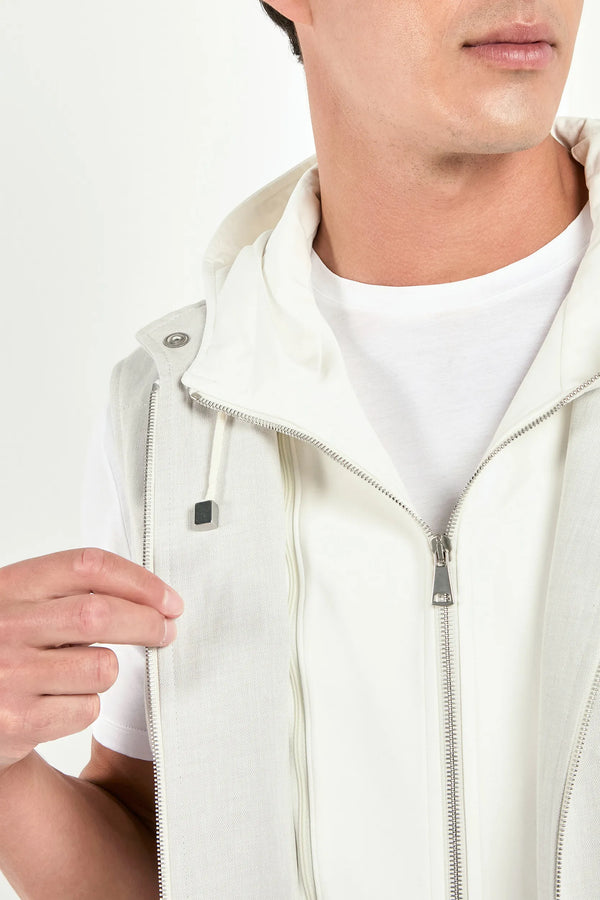 Person wearing a white vest over a white shirt on a plain background