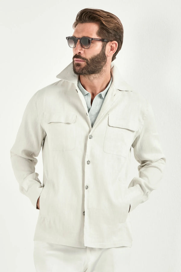 Person wearing a white jacket over a light green polo and white pants on a light background 