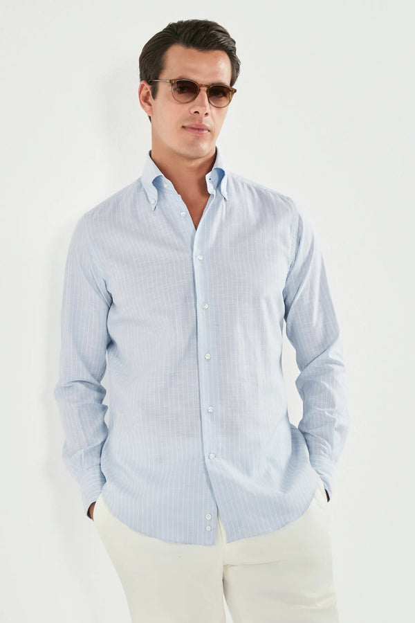 Man wearing a light blue striped shirt and sunglasses on a white background