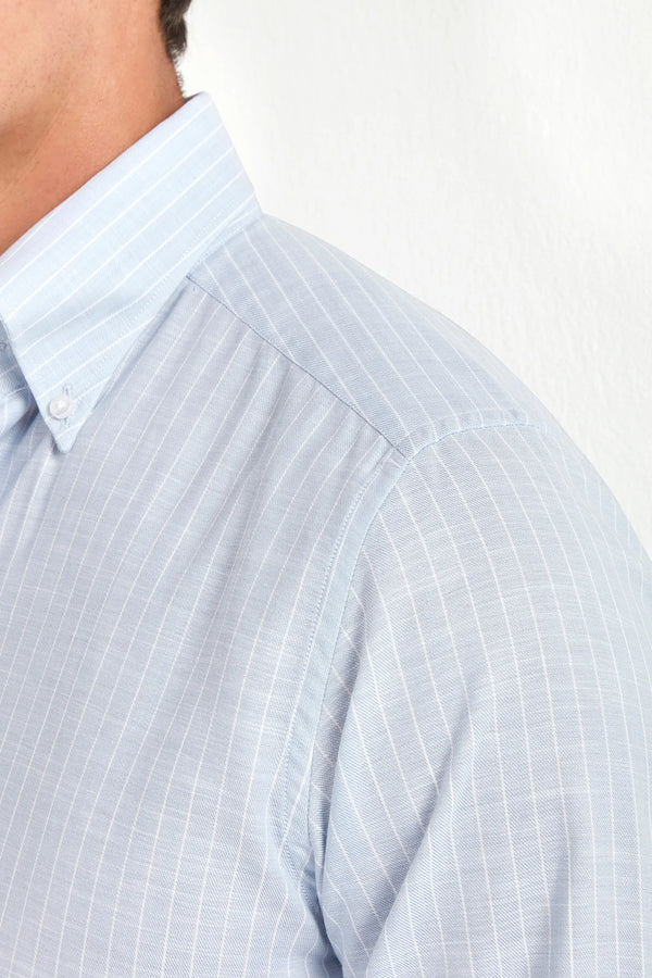 Close-up of a light blue checkered shirt with a white collar on a plain background