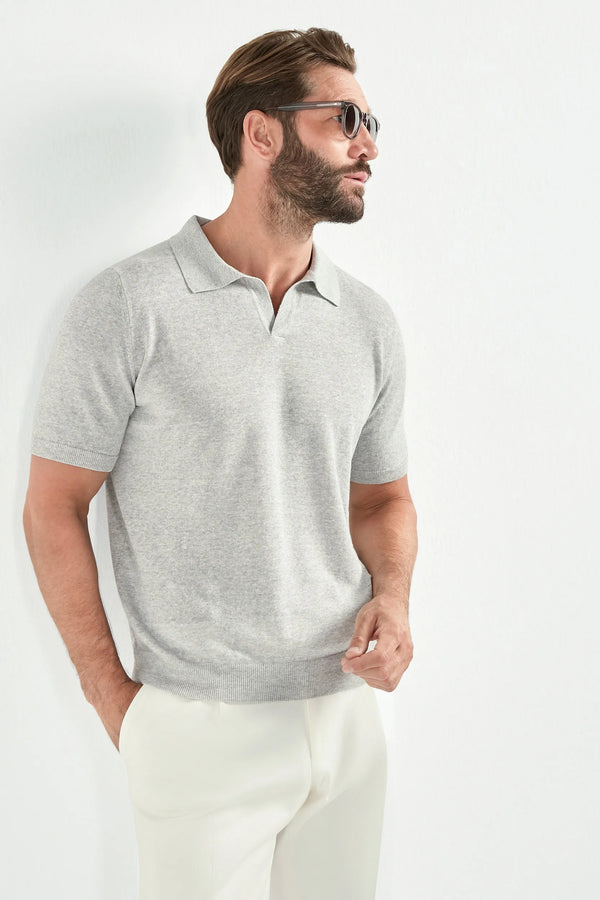 Man wearing a gray polo shirt and white pants on a light gray background