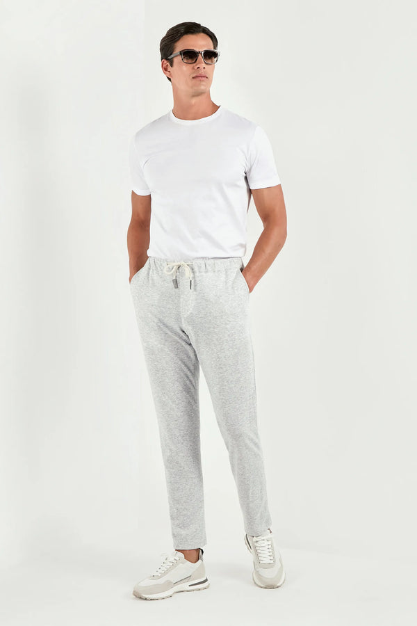 Man wearing a white t-shirt, gray jogger pants, and white sneakers on a white background