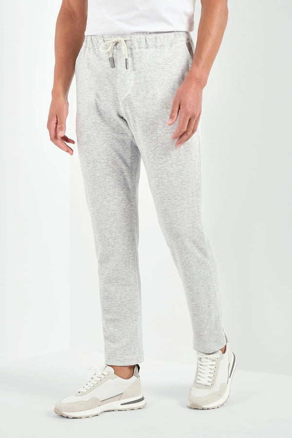 Person wearing gray sweatpants and white sneakers on a white background