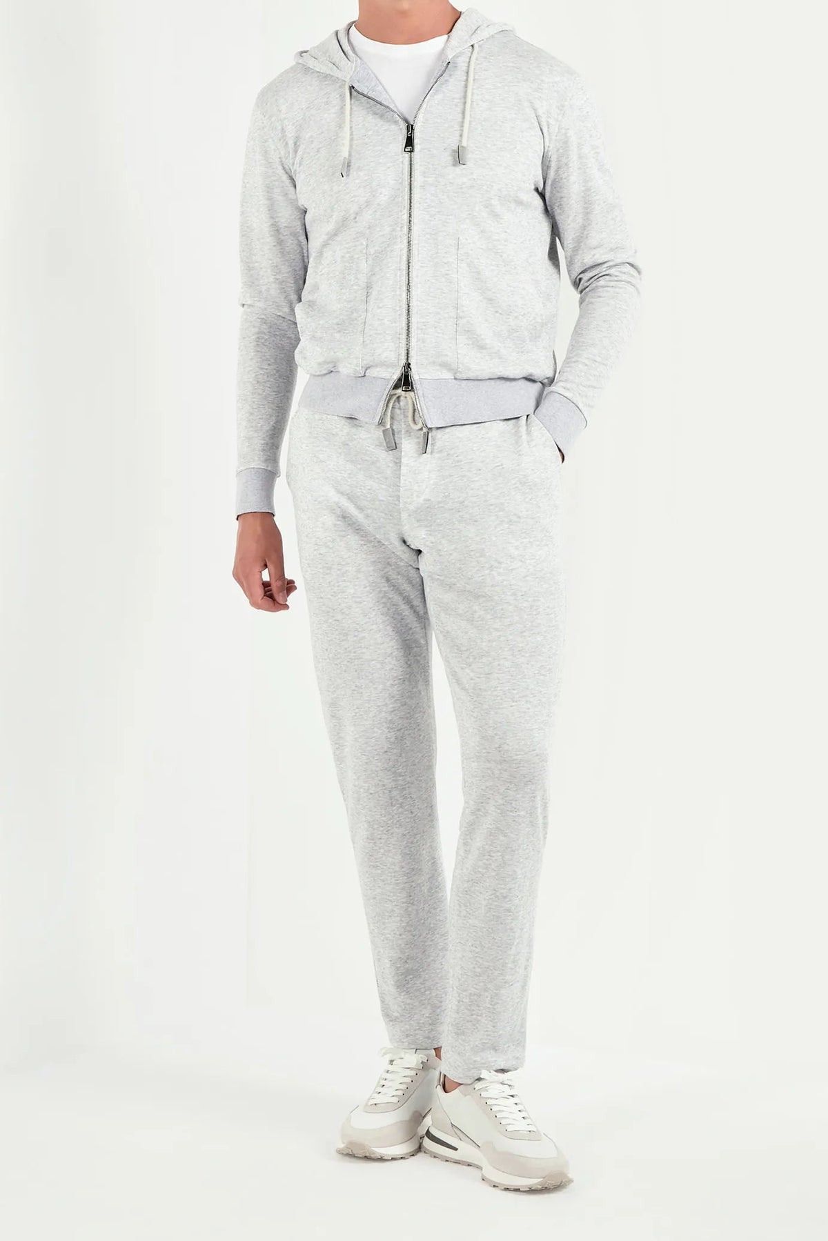 Man wearing a gray hoodie and pants with sunglasses on a white background