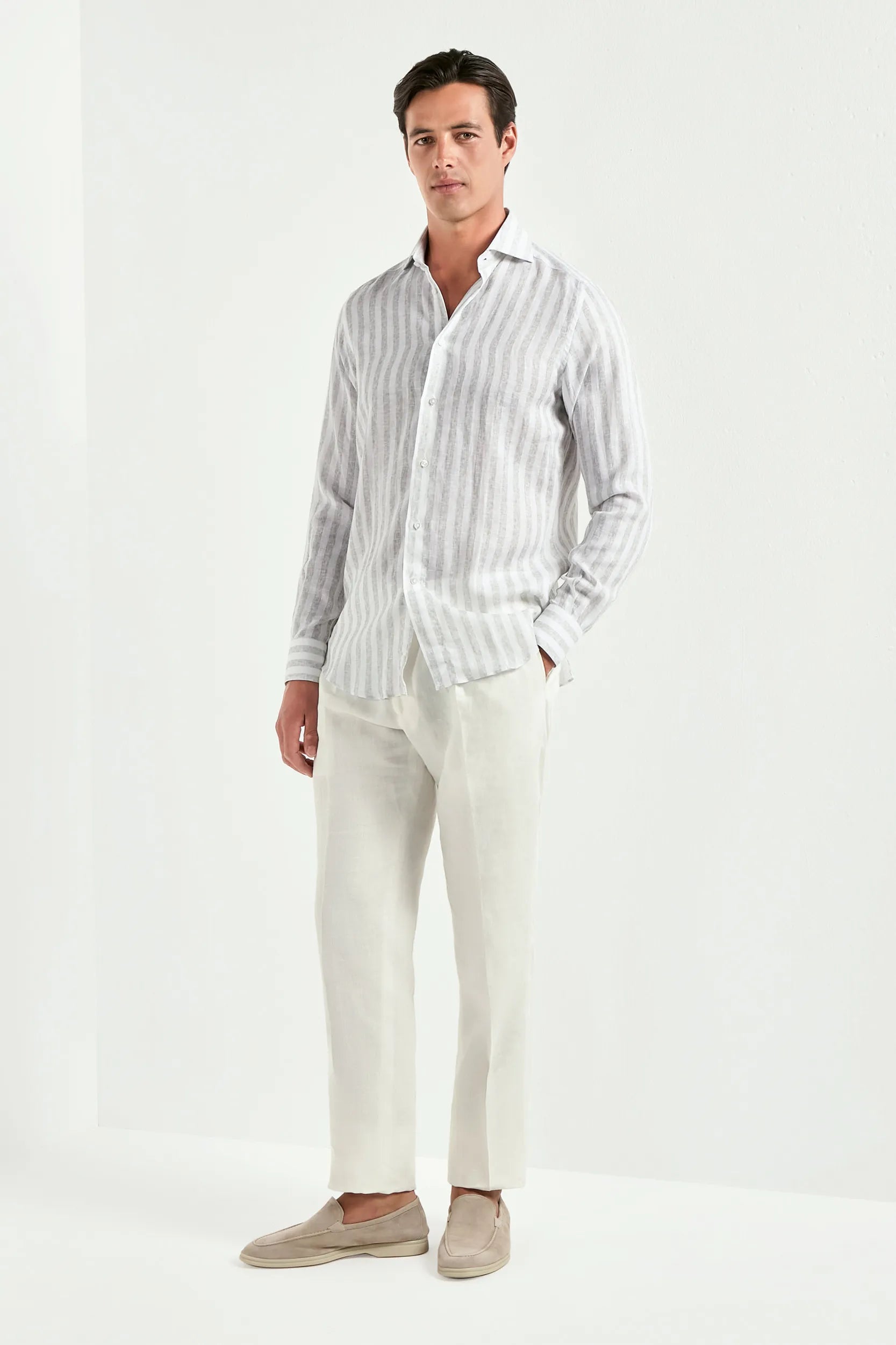 Man wearing a striped shirt and white pants on a white background