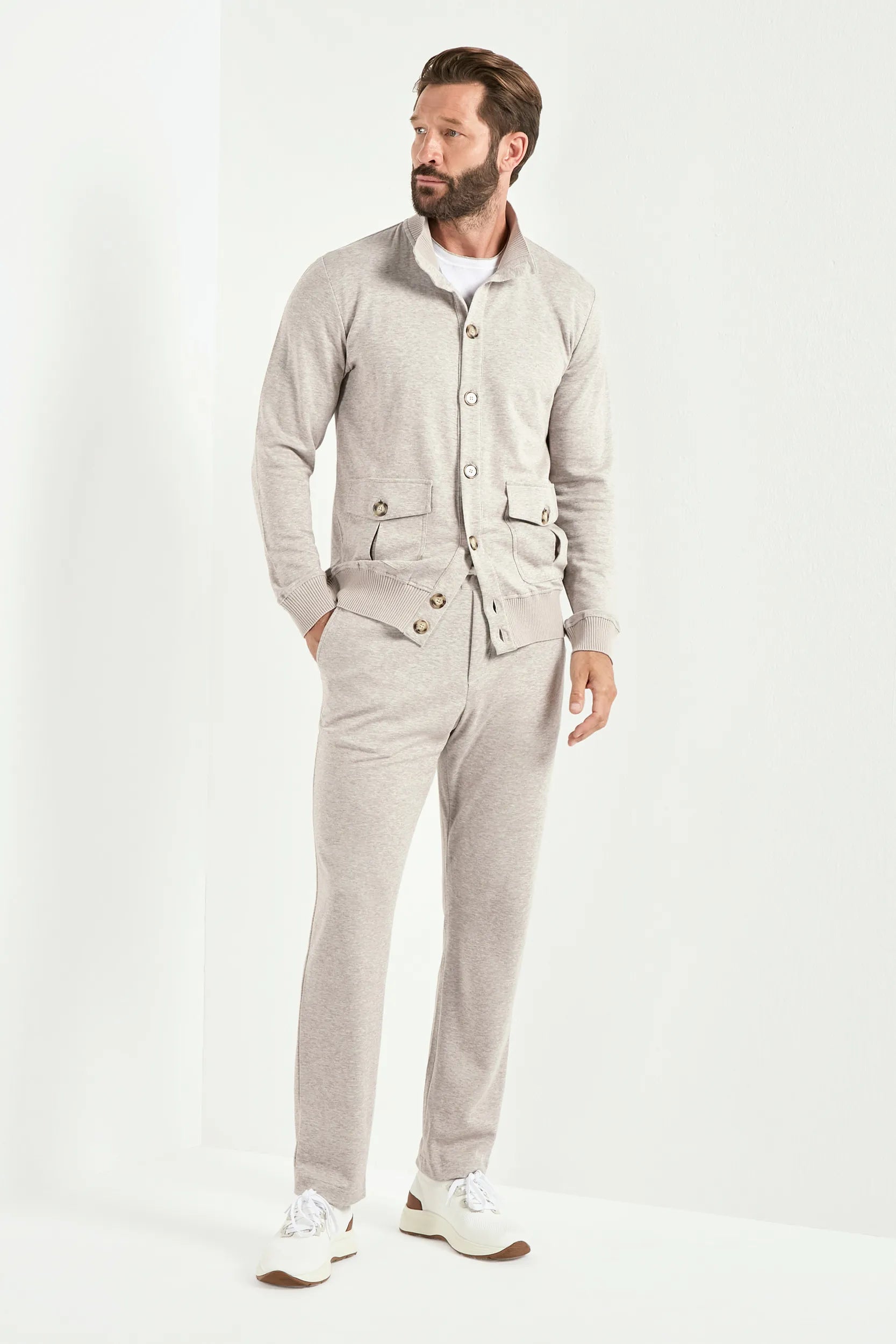 Man wearing a light gray outfit with a jacket and pants on a white background