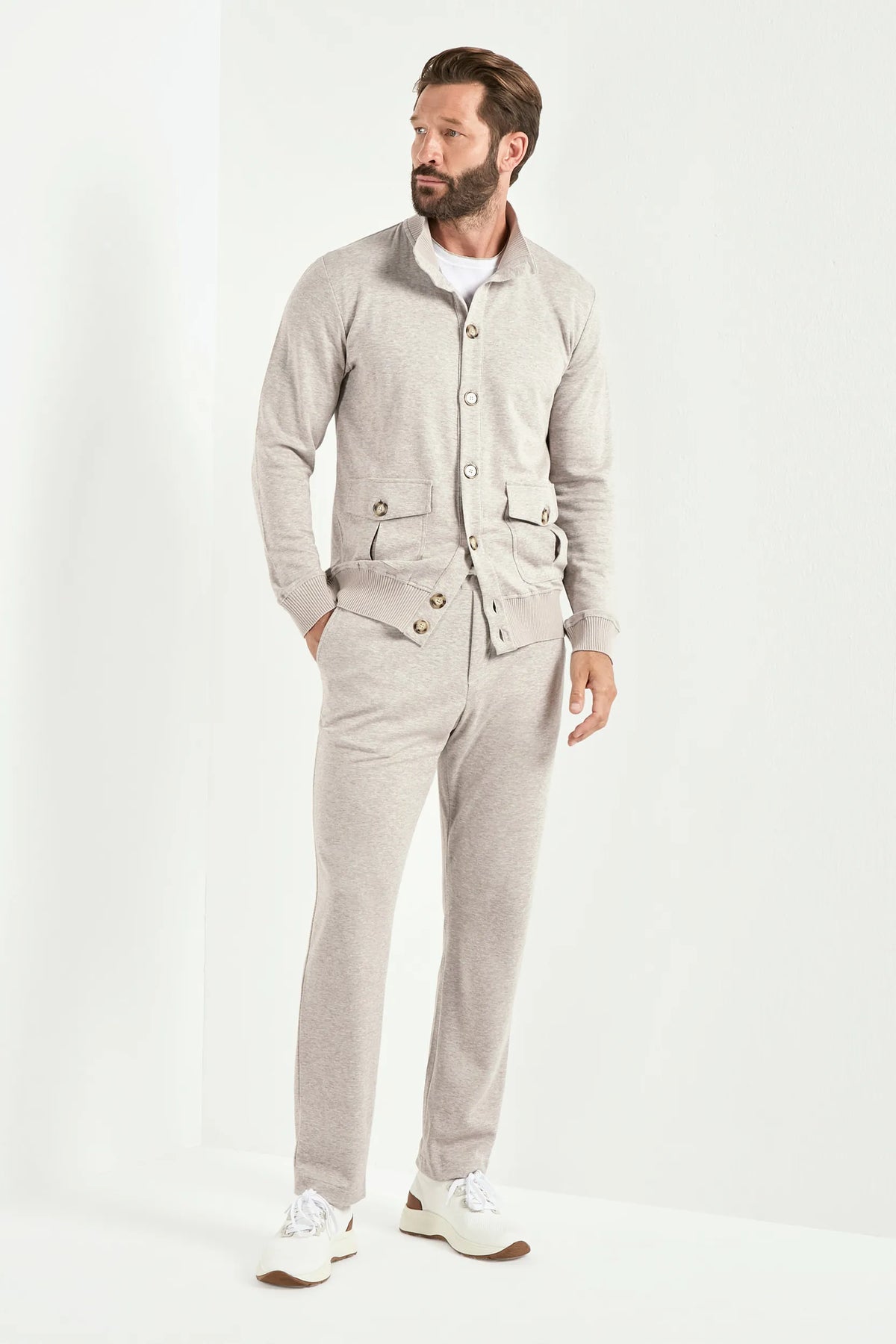 Man wearing a light gray outfit with a jacket and pants on a white background