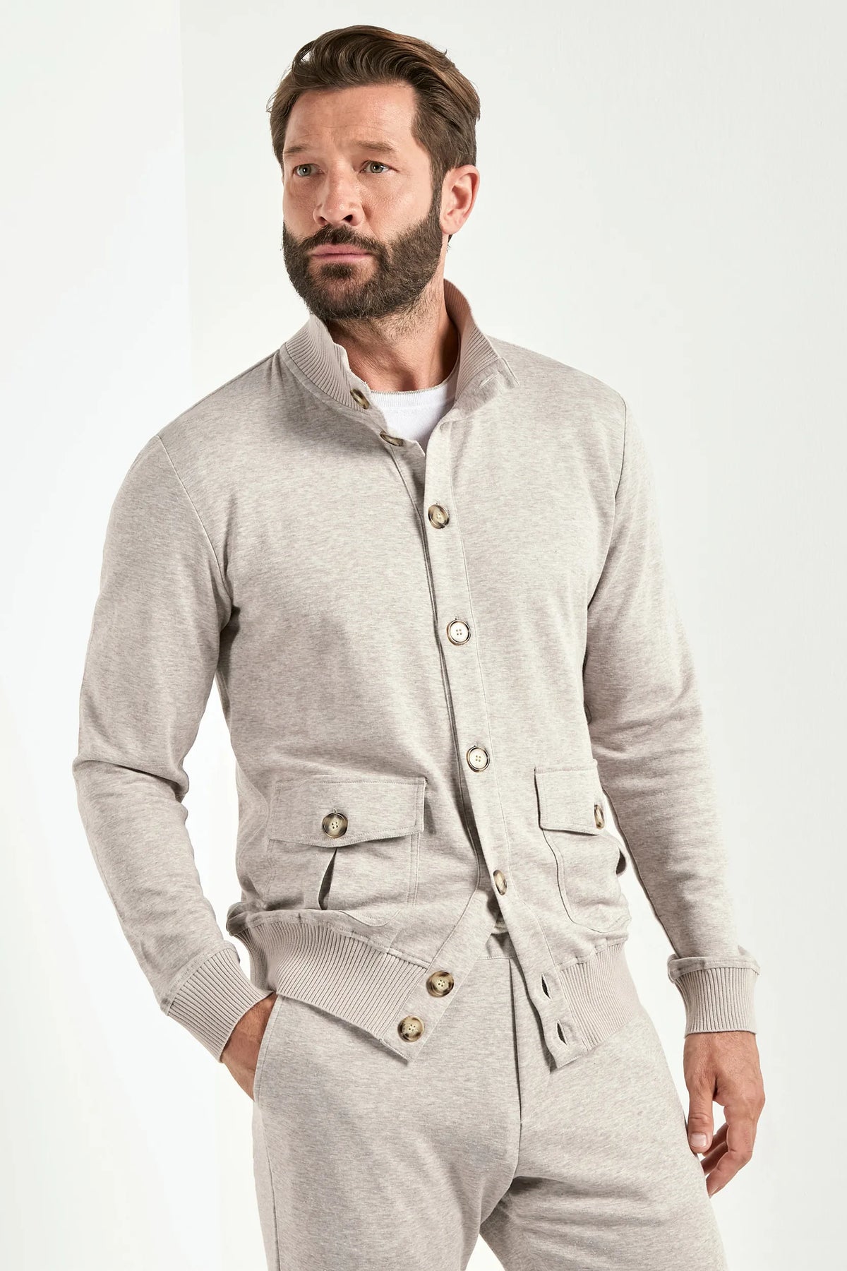 Man wearing a gray button-up outfit on a white background