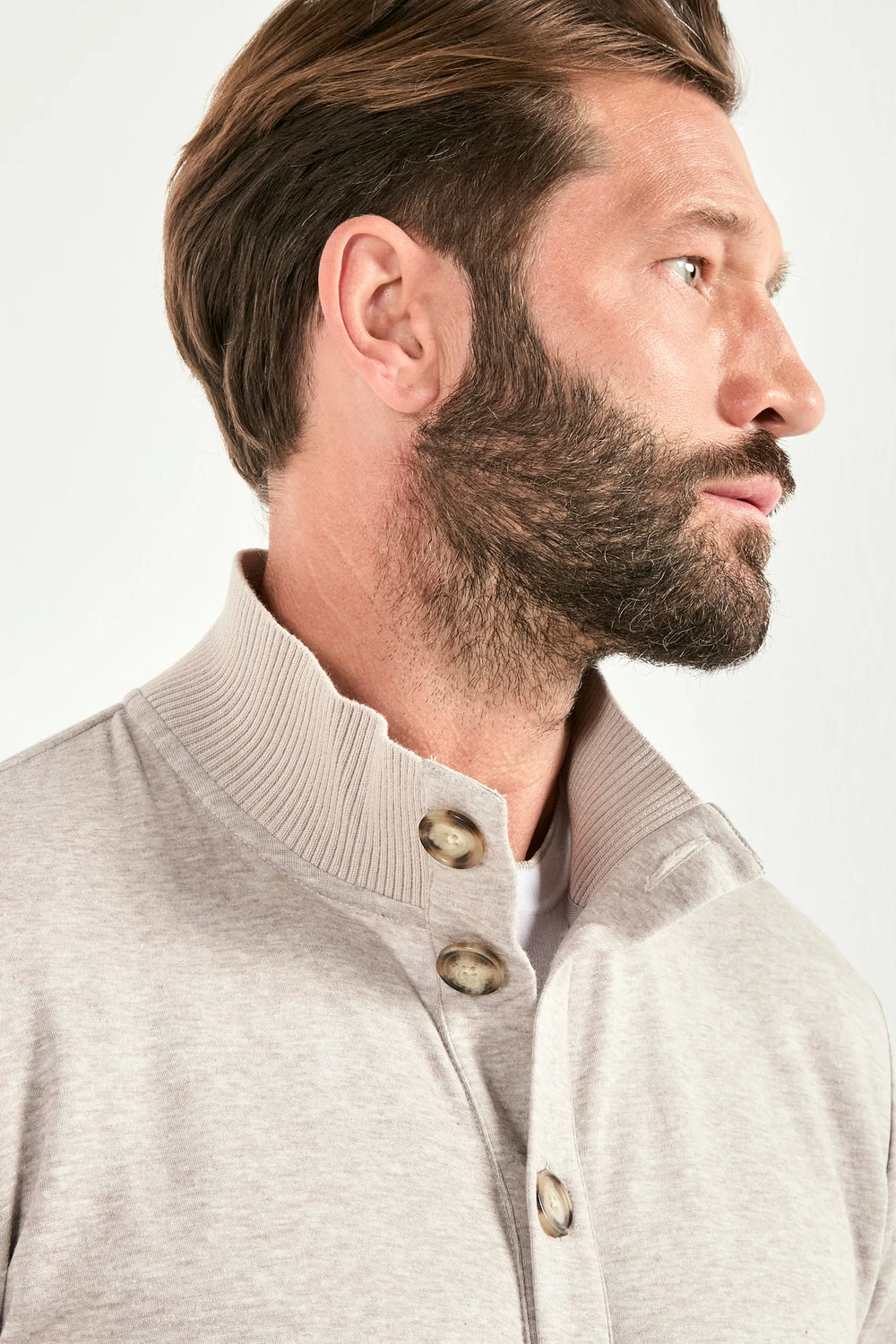 Man wearing a light gray button-up shirt against a white background