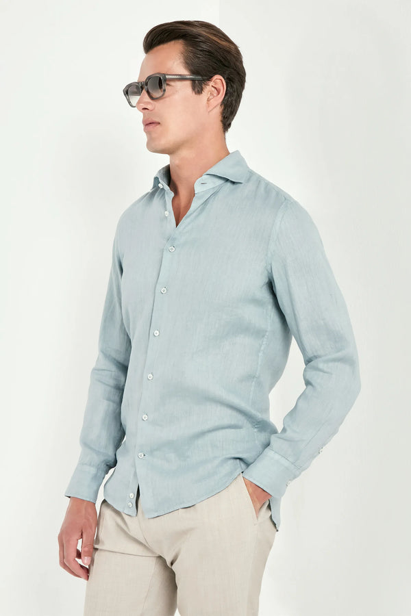 Man wearing a light blue button-up shirt and beige pants on a white background