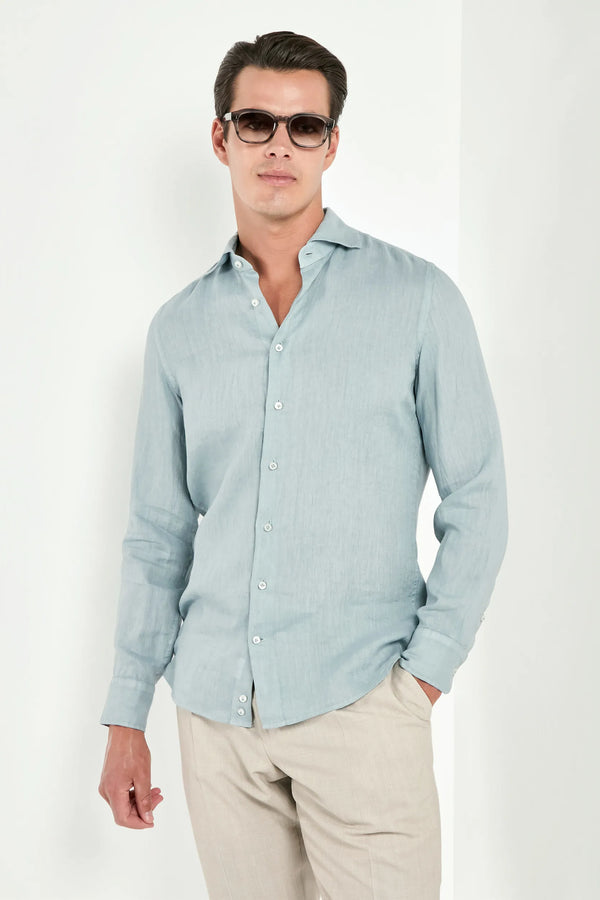 Man wearing a light blue button-up linen shirt and beige pants on a white background