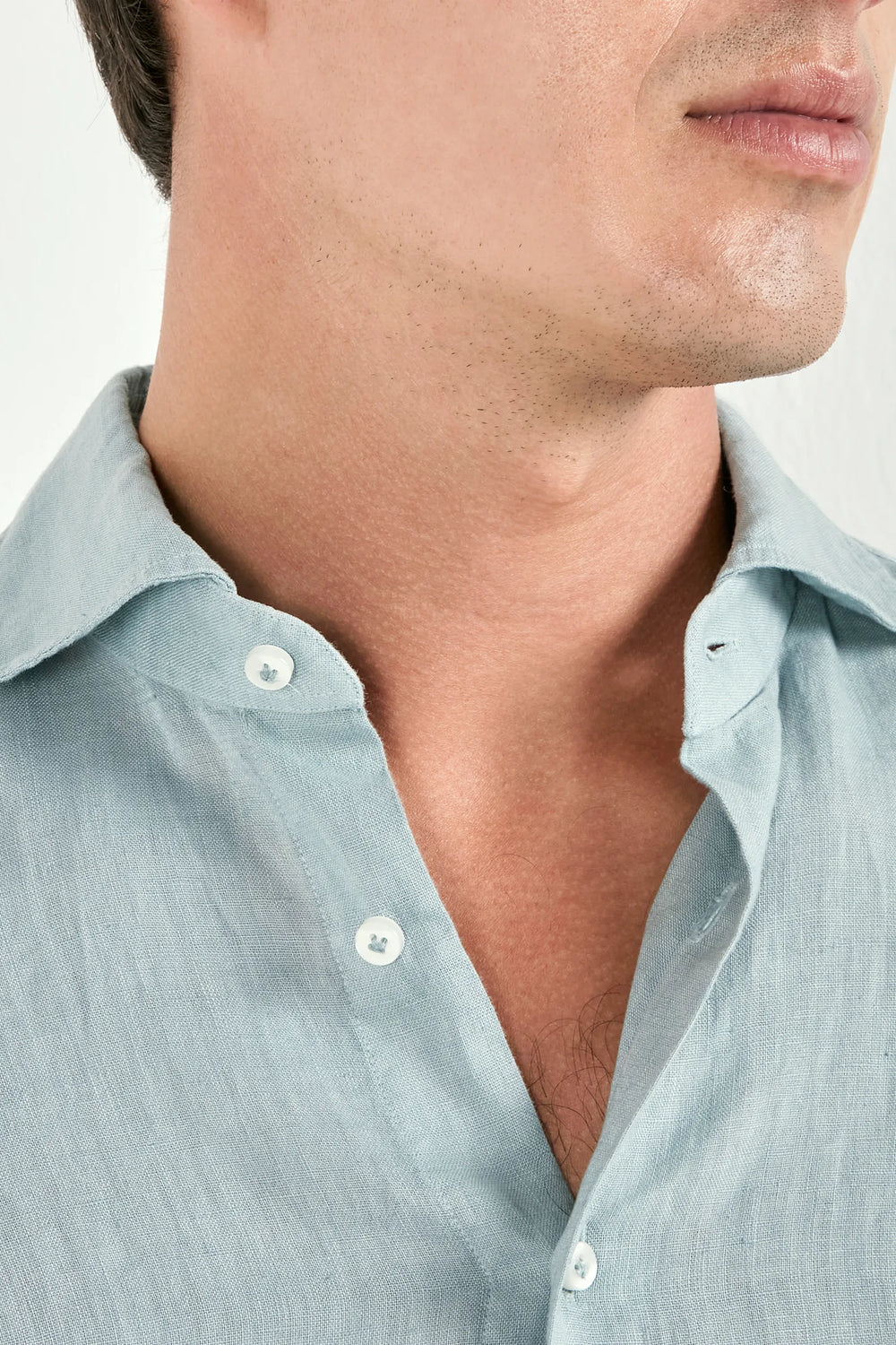 Close-up of a man wearing a light blue shirt with a white background