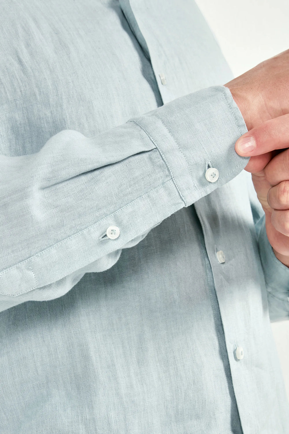 Light blue shirt with rolled-up sleeve and hand adjusting button