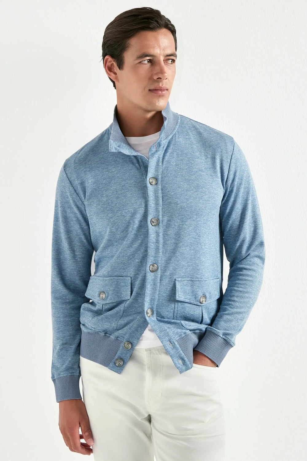 Man wearing a blue cardigan over a white shirt on a white background