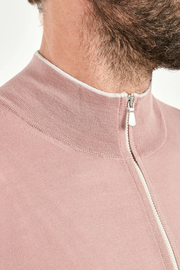 Close-up of a pink zip-up garment with a white zipper on a light background