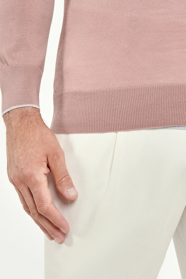 Close-up of a person wearing a pink sweater and white pants.
