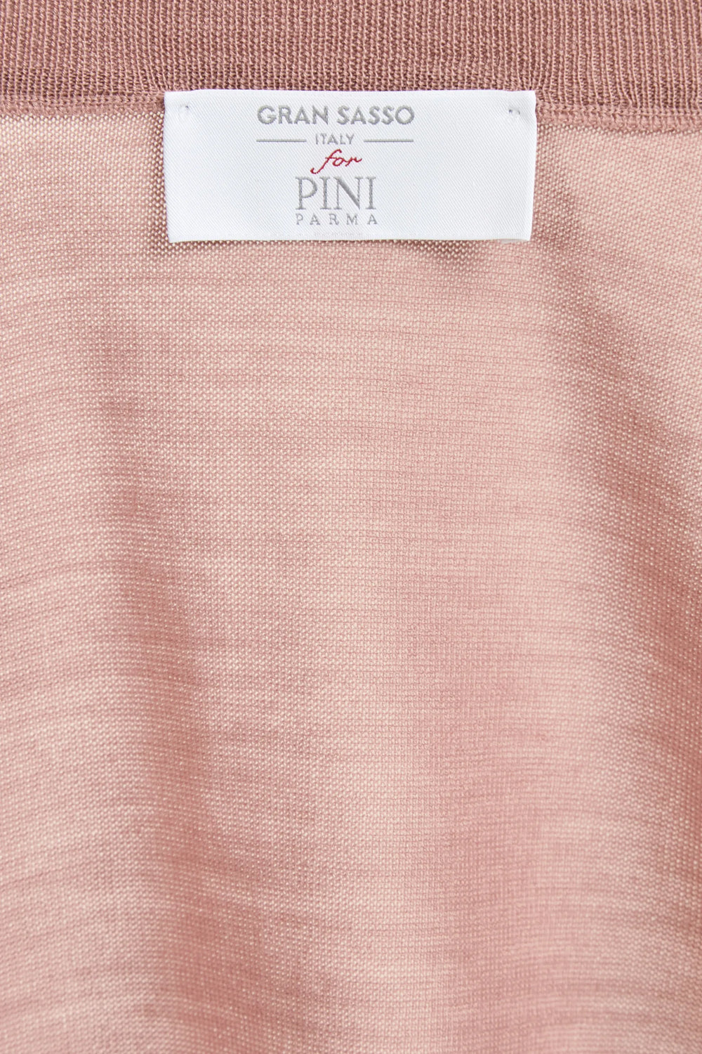 Close-up of a pink fabric with a Gran Sasso label on a white background
