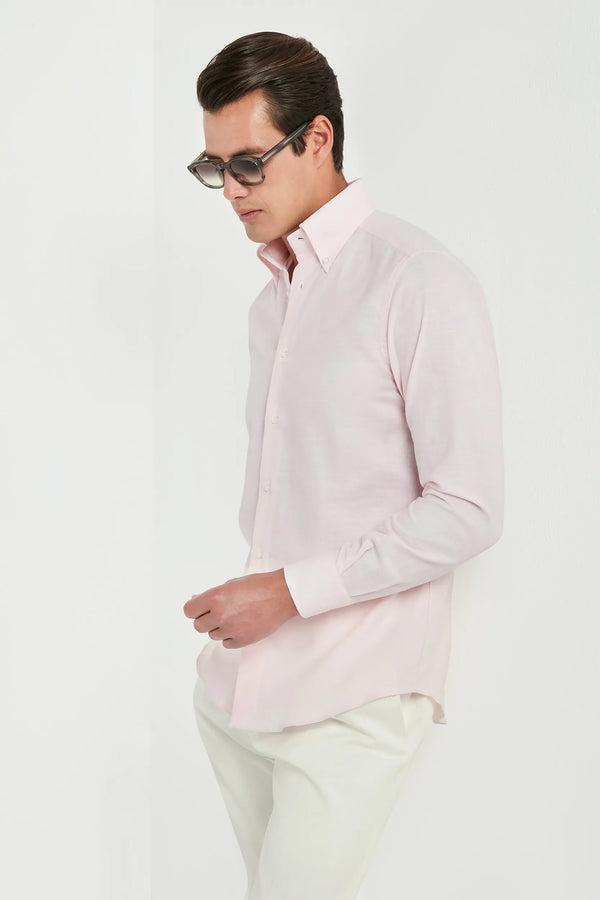 Man wearing a light pink shirt and white pants on a white background