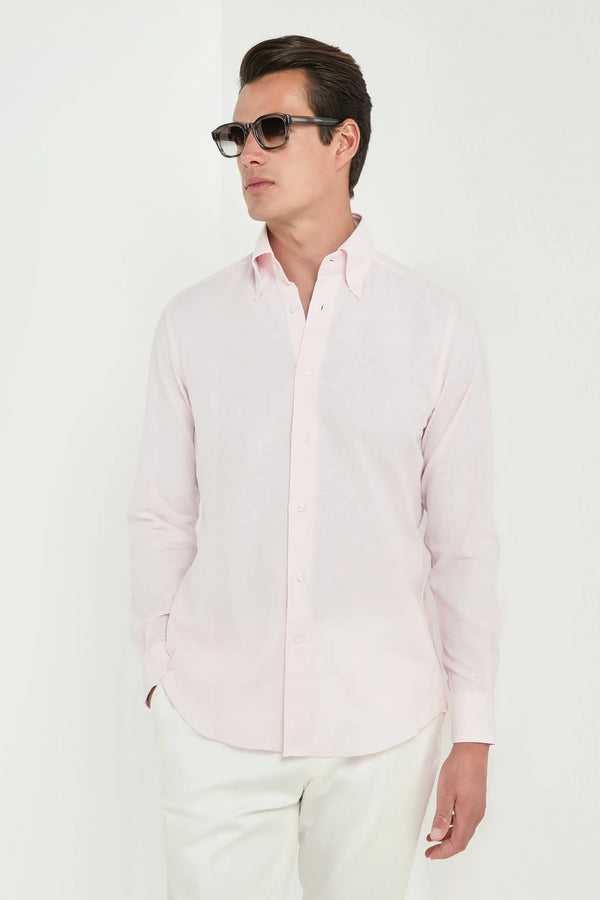 Man wearing a light pink shirt and white pants on a white background
