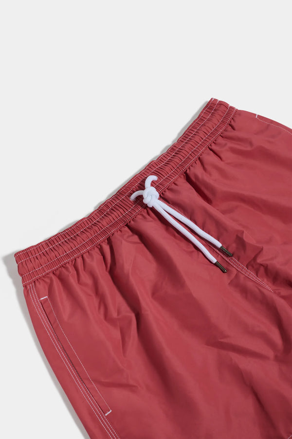 Red swim shorts with a white drawstring on a light gray background