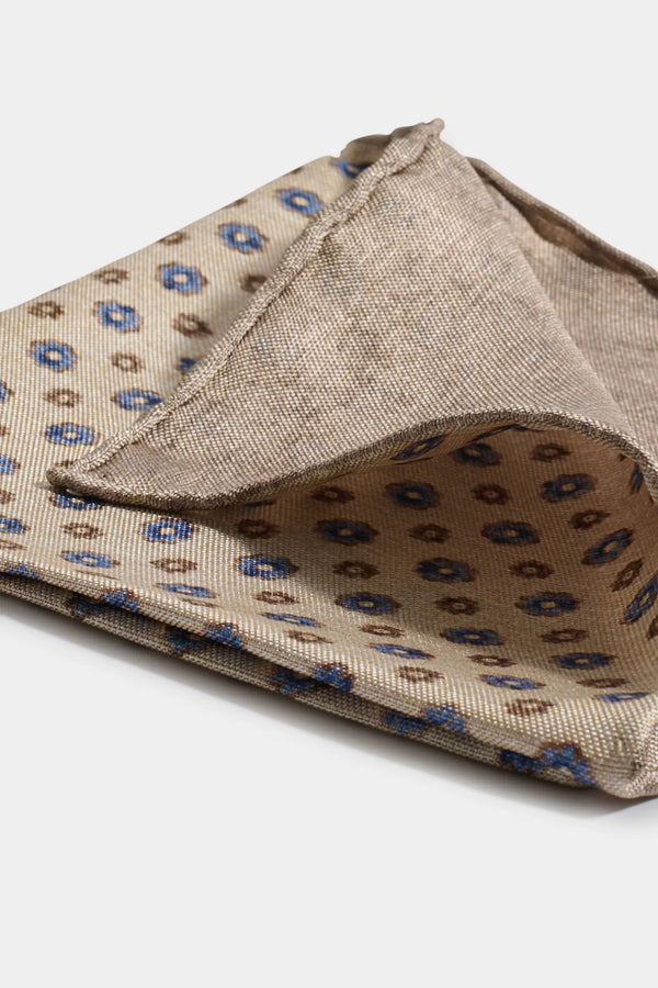 Folded beige fabric with blue floral pattern on a white background