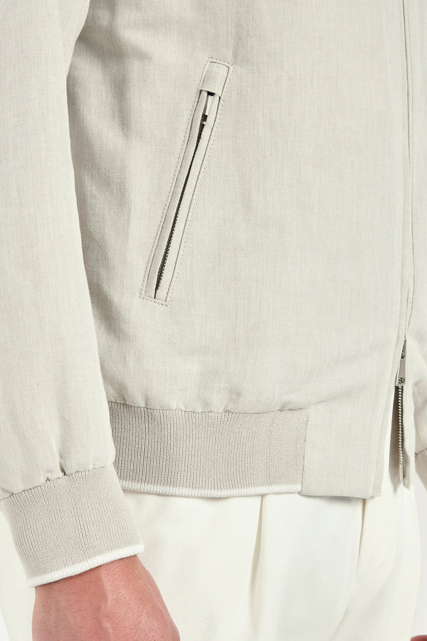 Close-up of a light gray jacket with a zipper on a neutral background