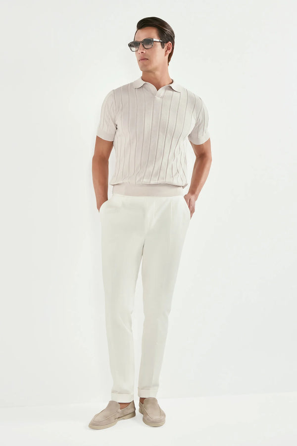 Man wearing a white polo shirt and pants with sunglasses on a white background