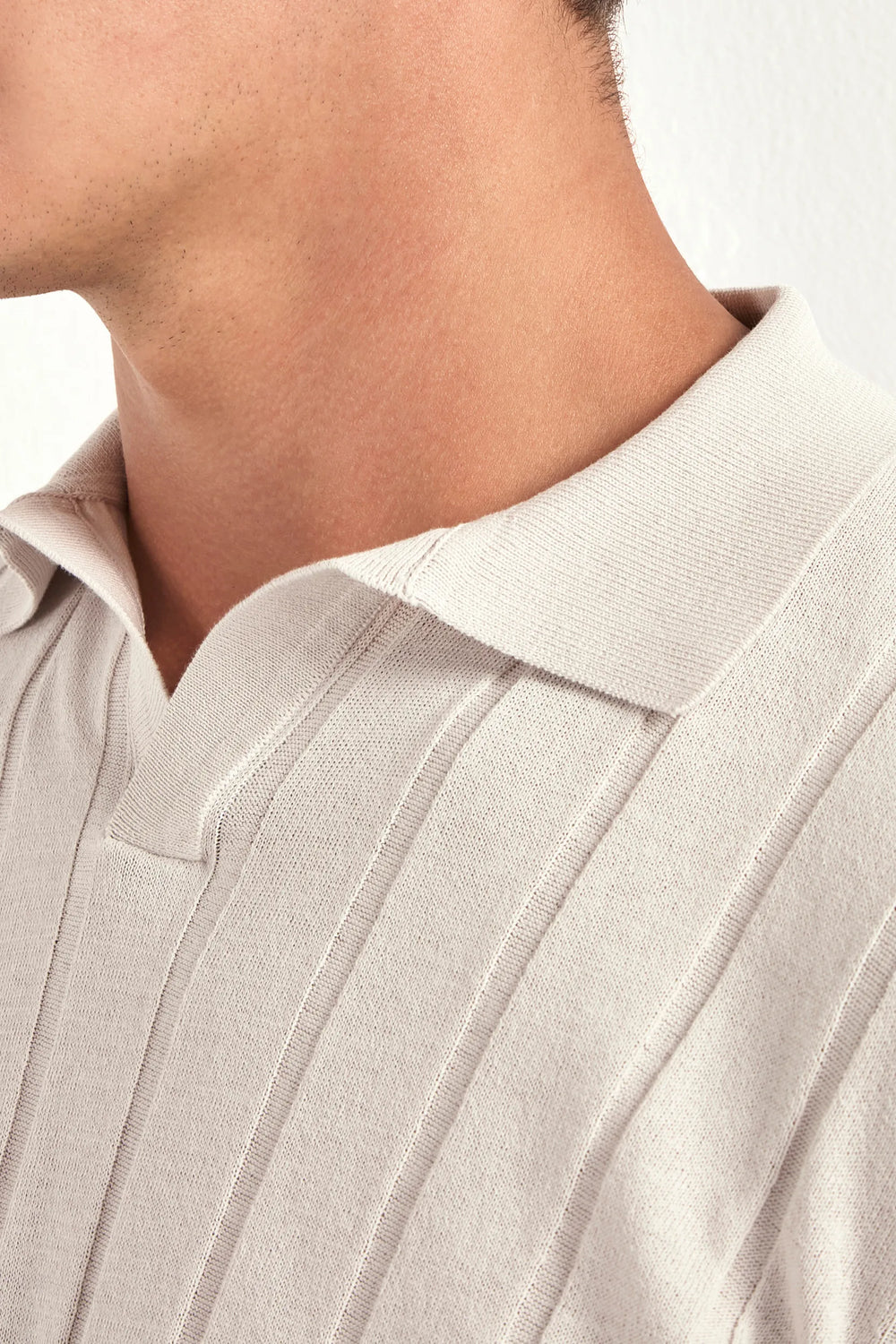 Close-up of a person wearing a light-colored shirt with a collar.