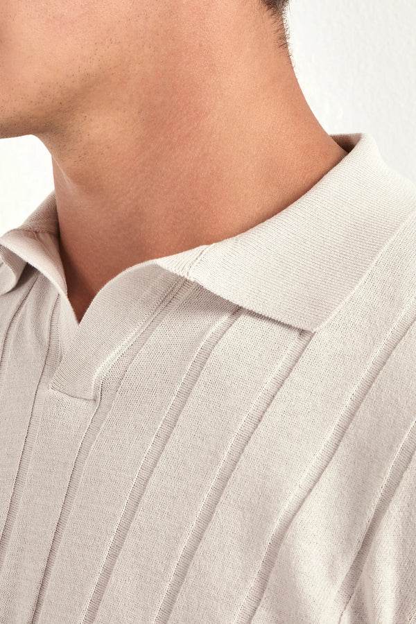 Close-up of a person wearing a light-colored shirt with a collar.