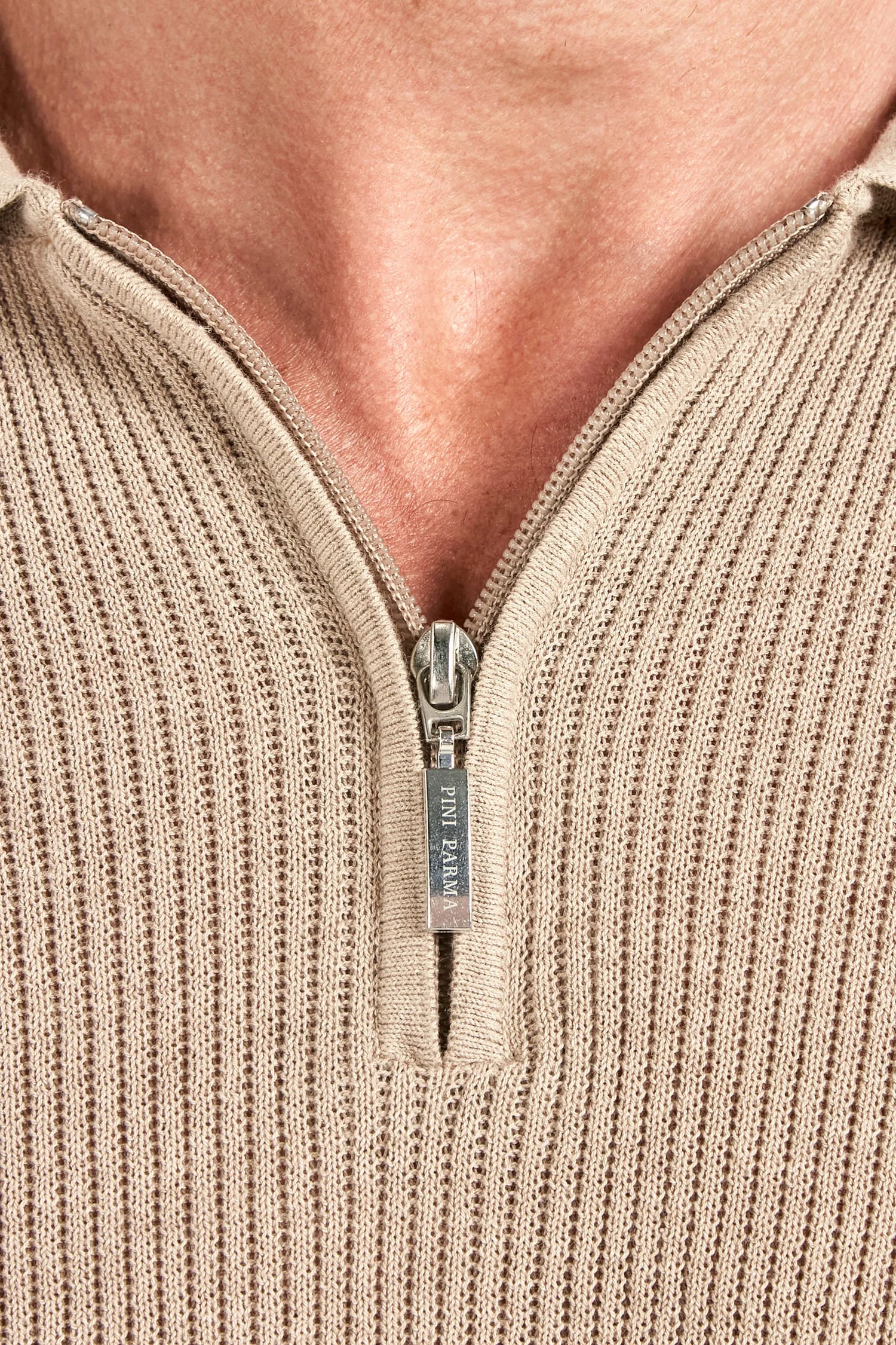 Close-up of a beige ribbed sweater with a zipper