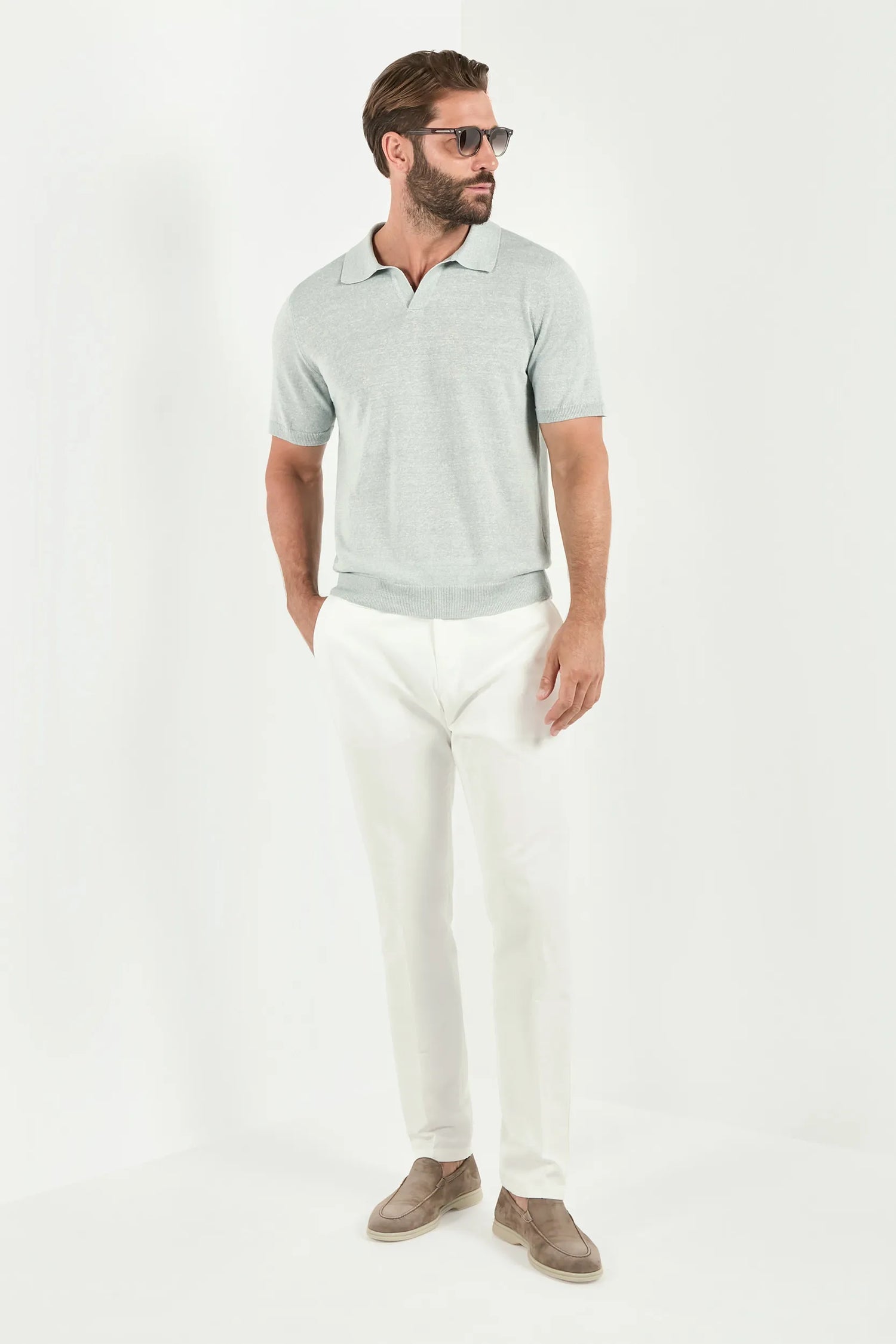 Man wearing a light gray polo shirt and white pants on a white background