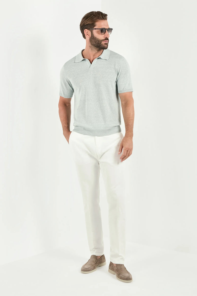 Man wearing a light gray polo shirt and white pants on a white background