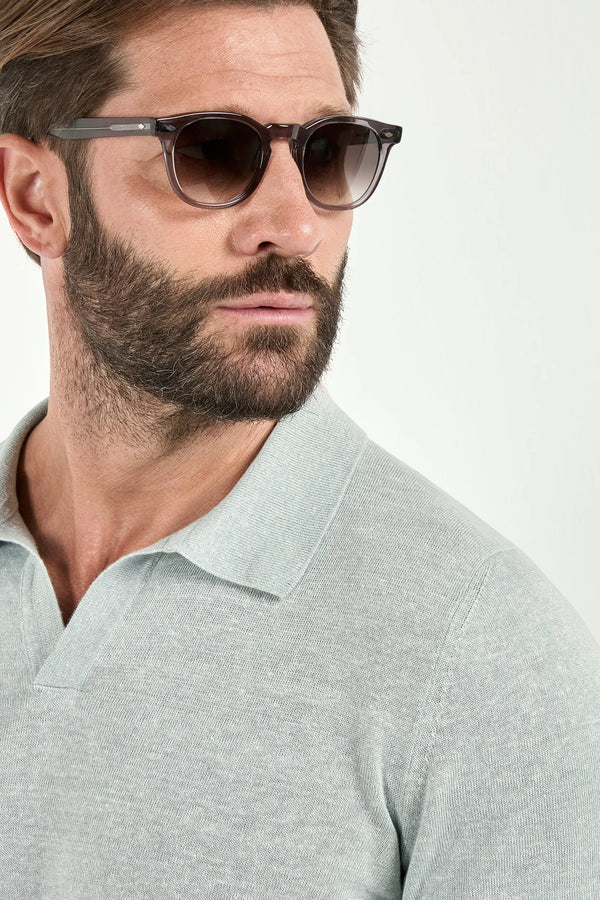 Man wearing sunglasses and a light gray polo shirt on a white background